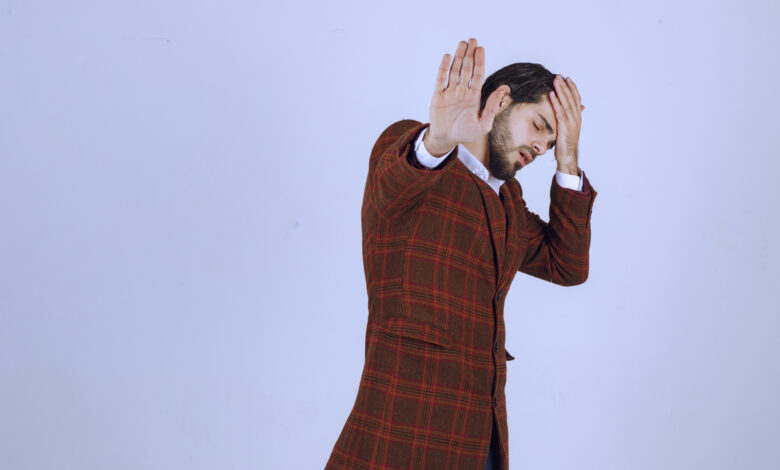 Man in checked jacket putting his head as he has headache or feels tired