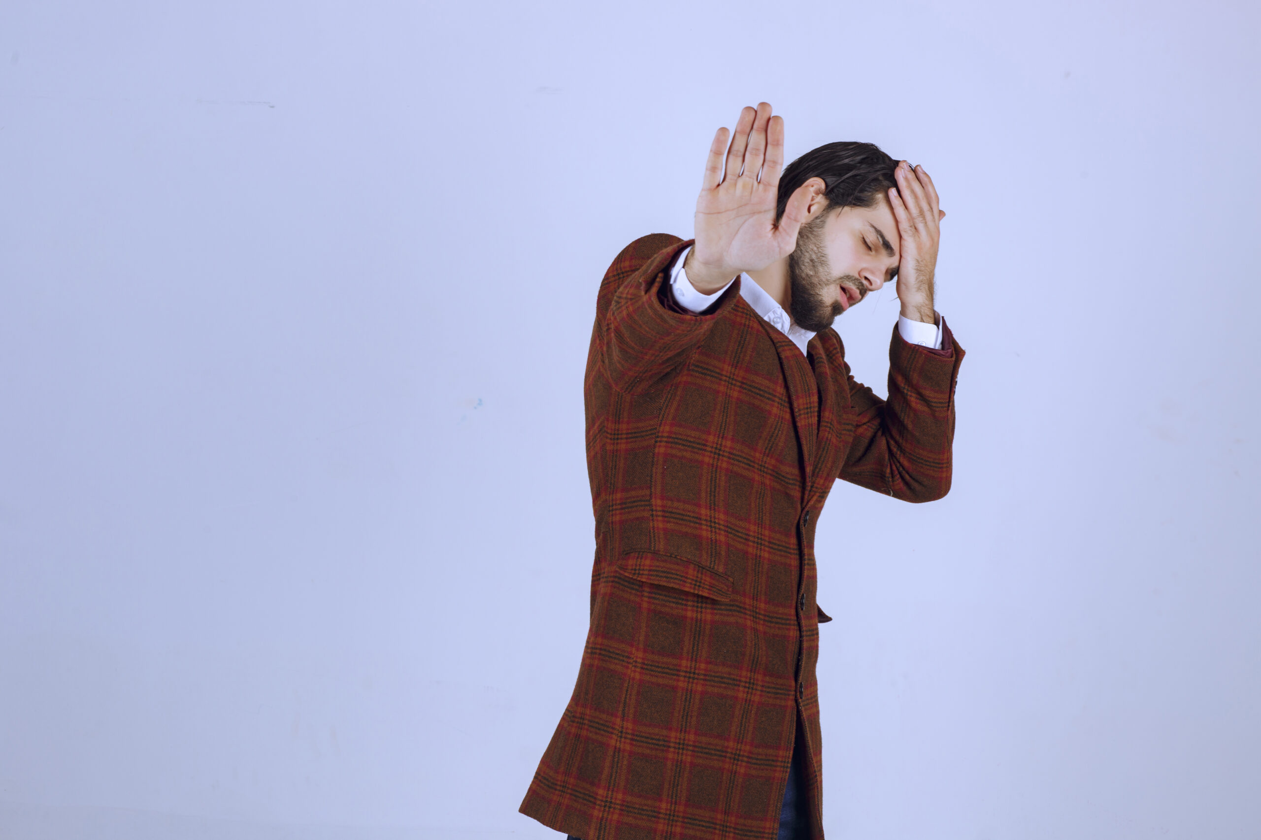 Man in checked jacket putting his head as he has headache or feels tired